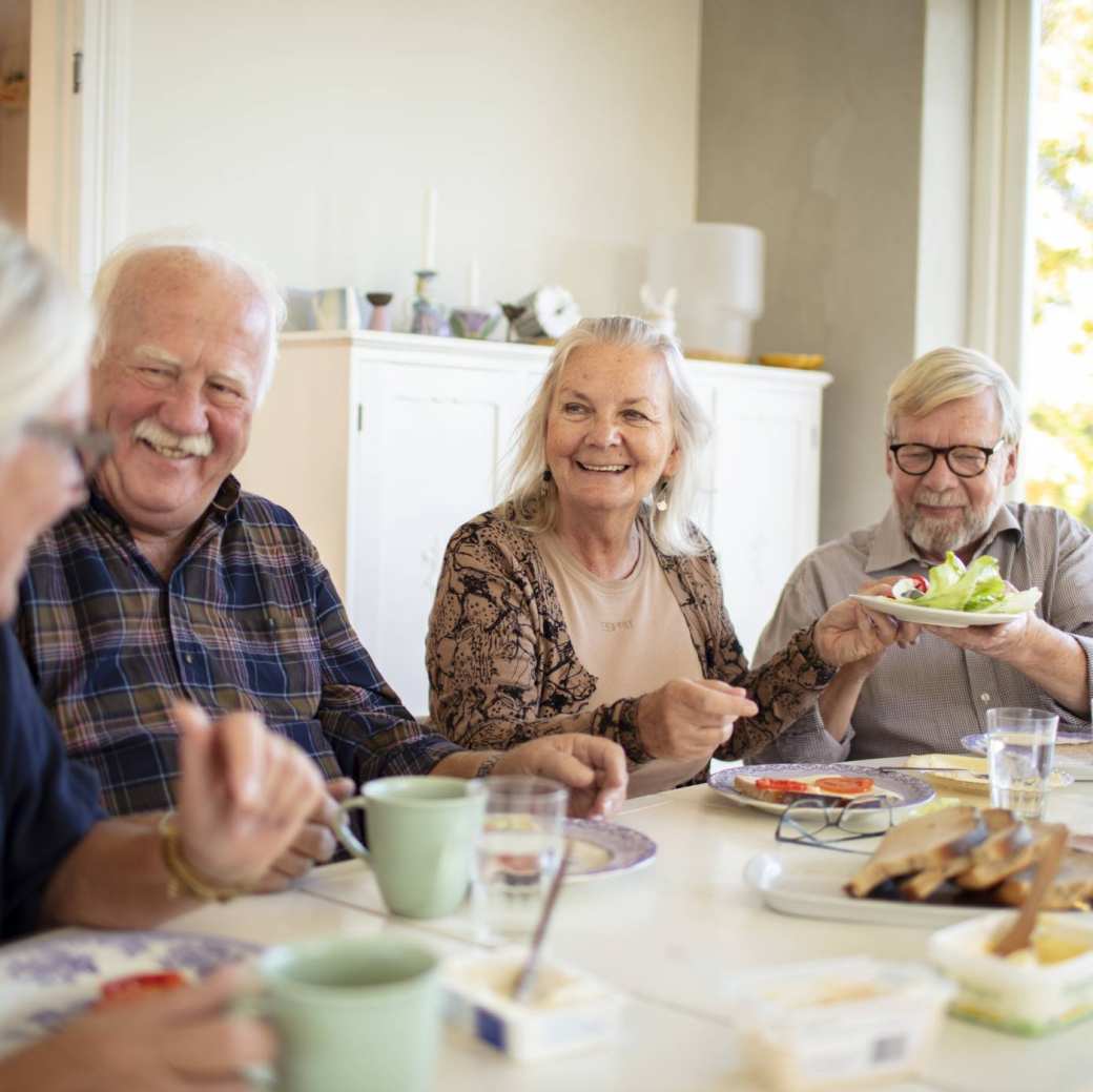 Groep ouderen aan tafel tijdens het ontbijt in een verpleeghuis