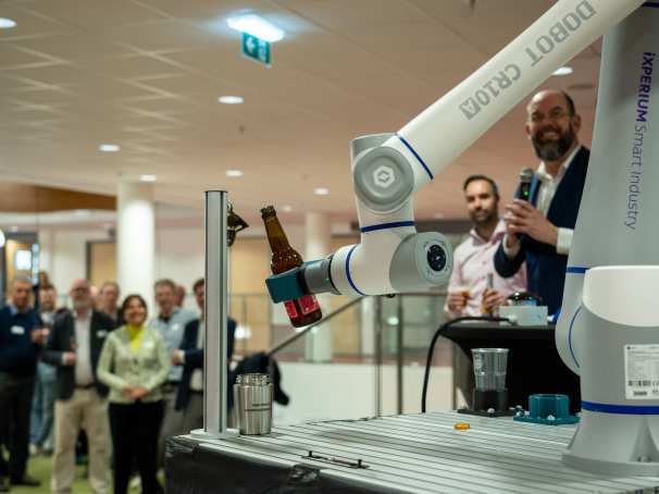 Het iXperium is geopend op 16 april. Een cobot pakt het door AI samengestelde biertje en schenkt een glas in.