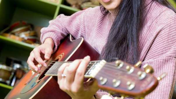 Student HAN Pabo Arnhem speelt gitaar en lacht.