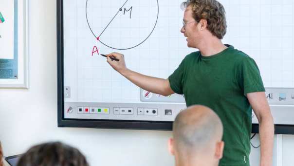 Leraar Wiskunde legt aan zijn klas de stelling van Thales uit op het bord
