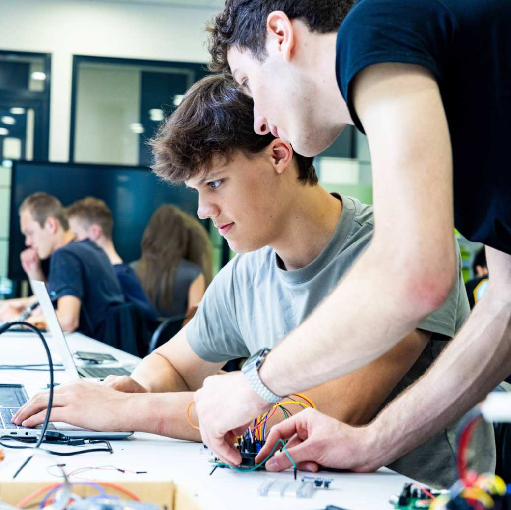 Studenten embedded systems engineering werken samen op de laptop in het lab.