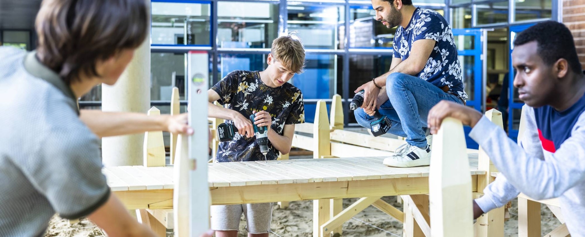 4 studenten civiele werken aan de houten steiger onder het gebouw van de opleiding 