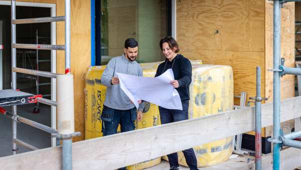 bouwkundige bespreekt op een steiger het bouwplan