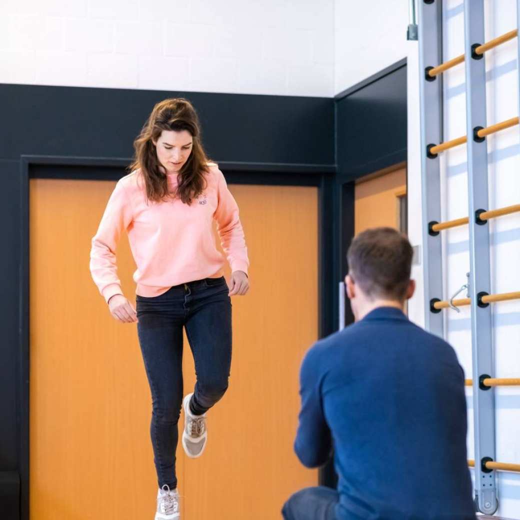 Student staat op een been, terwijl een ander toekijkt.