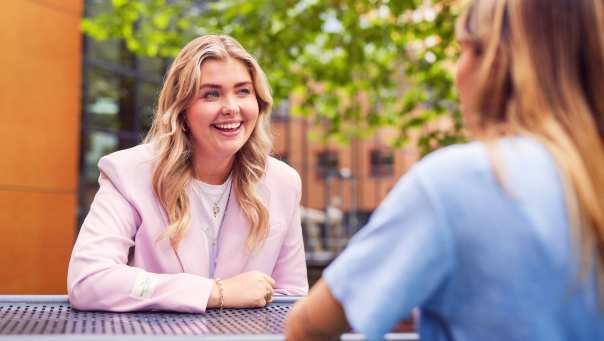 werving voltijd campagne, twee studentes in gesprek aan een picnictafel in de binnentuin.