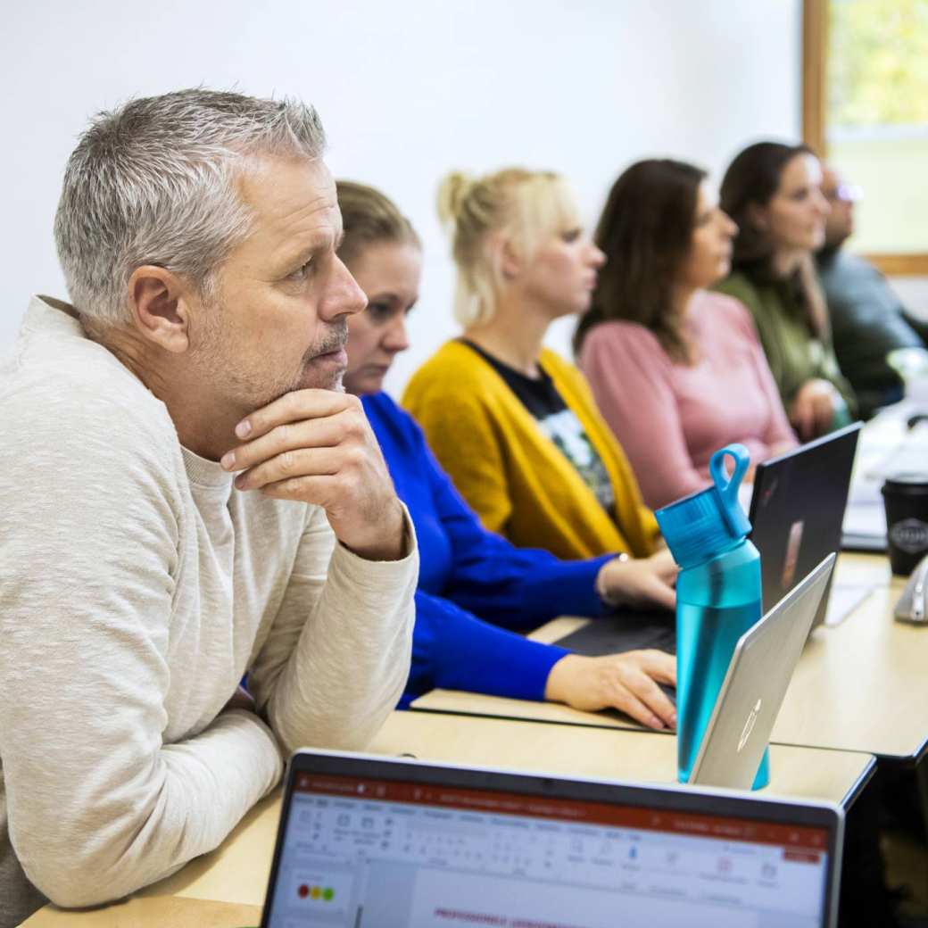 Student MOVEL kijkt vragend, terwijl hij in de klas zit naast zijn medestudenten.