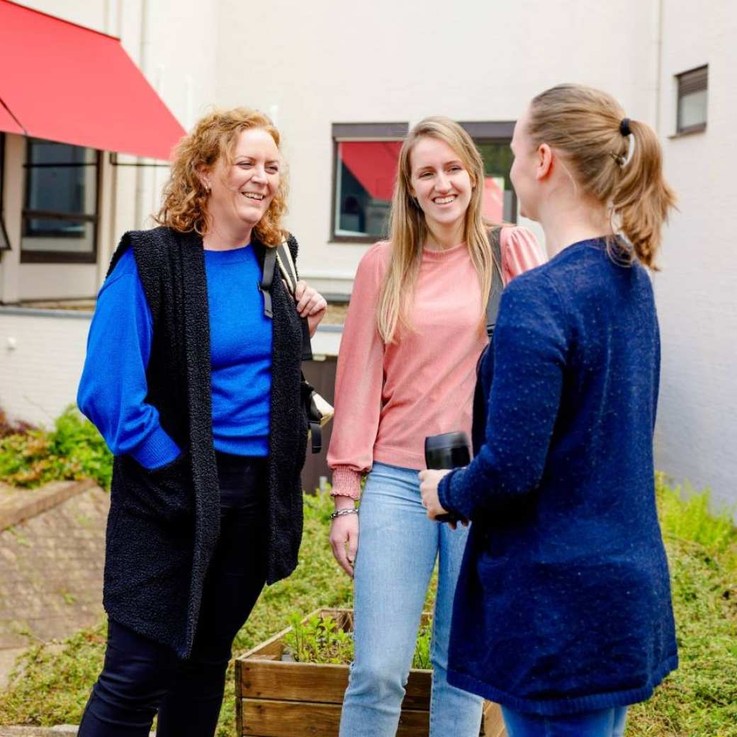 Twee mannen en twee vrouwen staan pratend op de gang