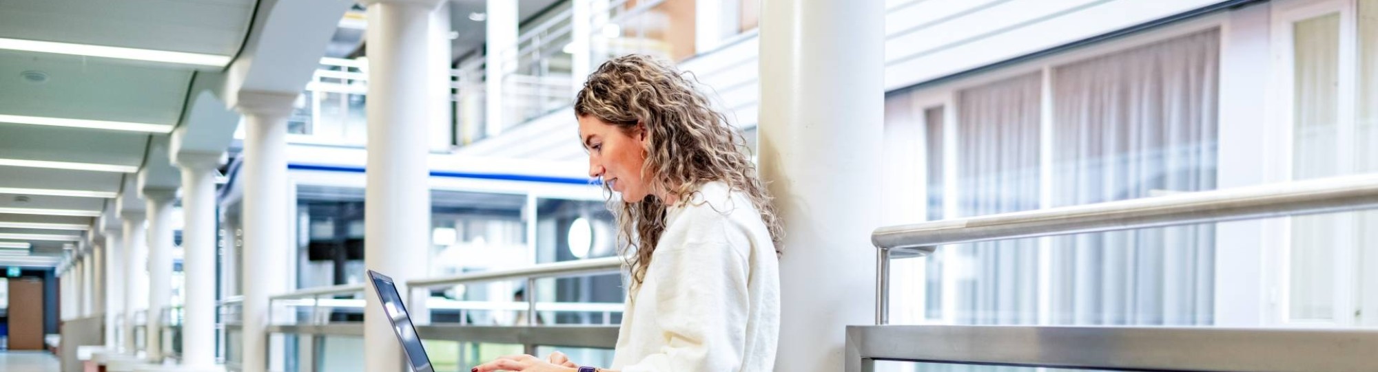 Student van de bachelor Commerciële Economie deeltijd, duaal in gang met laptop. 