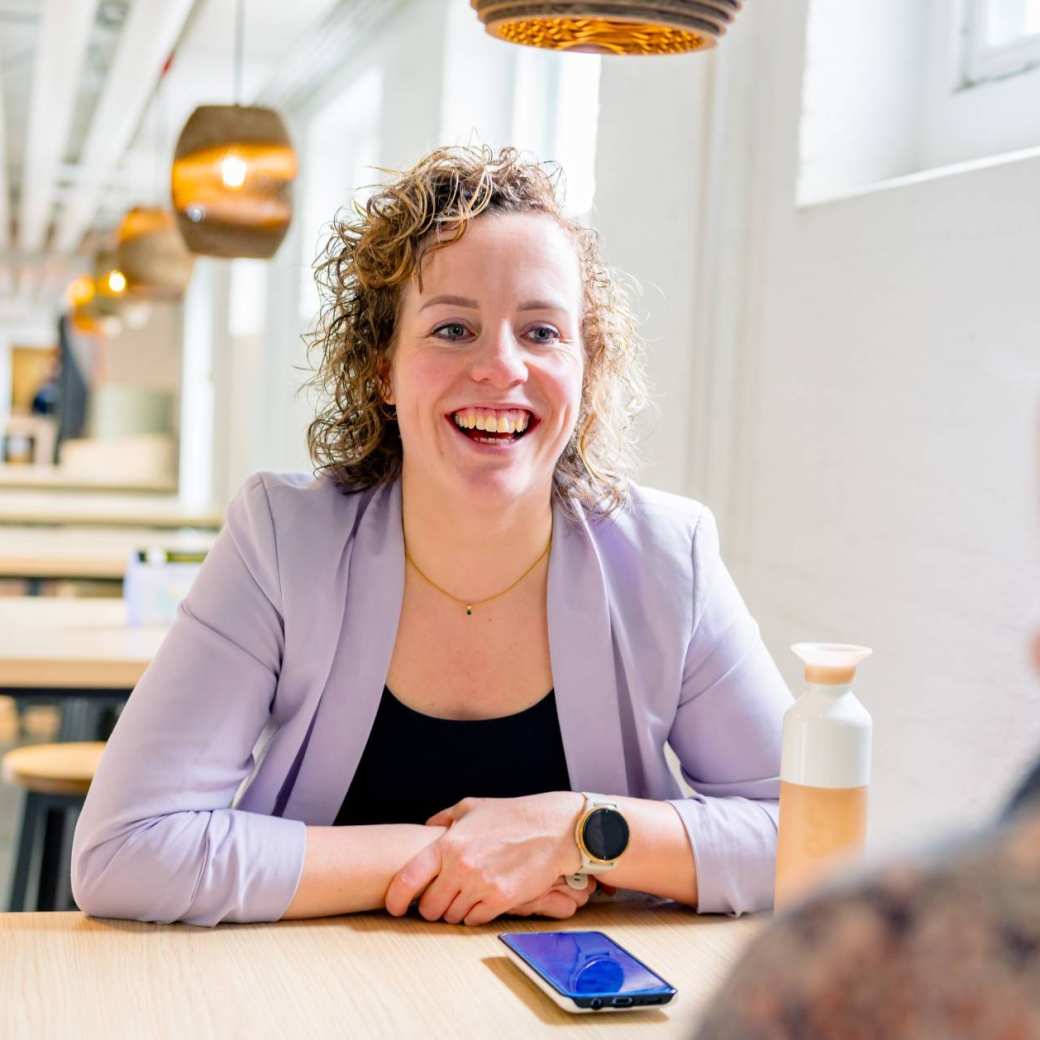 Vrouw in gesprek, moet lachen. Tijdens de cursus acute pijn service, in de kantine.