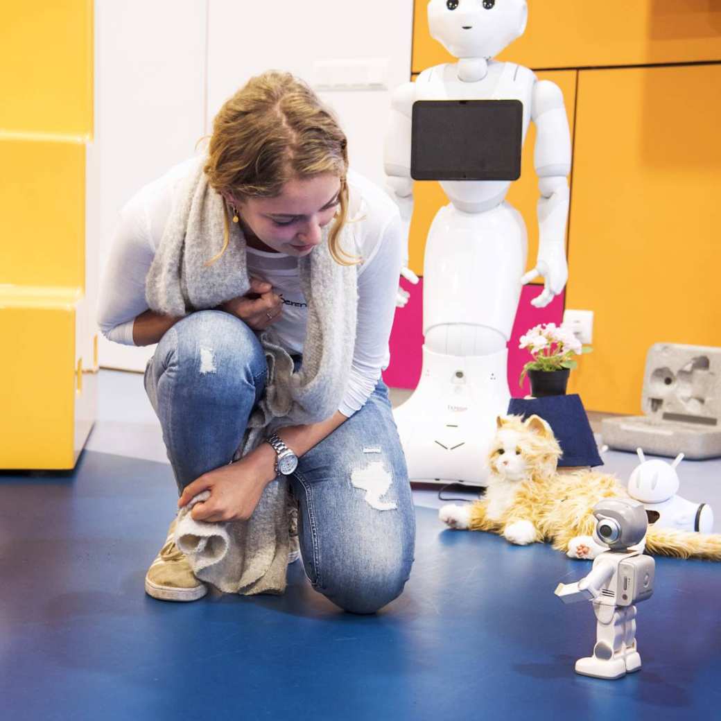 student kijkt gehurkt naar kleine robot tijdens iXbites