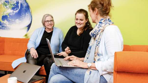Drie vrouwen in overleg op een oranje bank