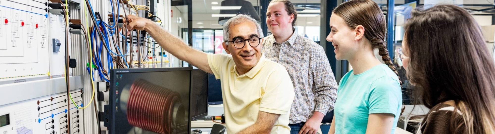 Een docent elektrotechniek geeft uitleg aan studenten in het hoogspanningslab.