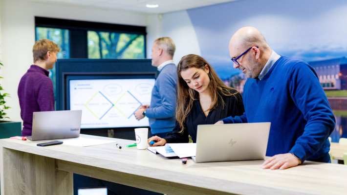 Studenten van de master Business Sales in overleg, samenwerken op laptop.