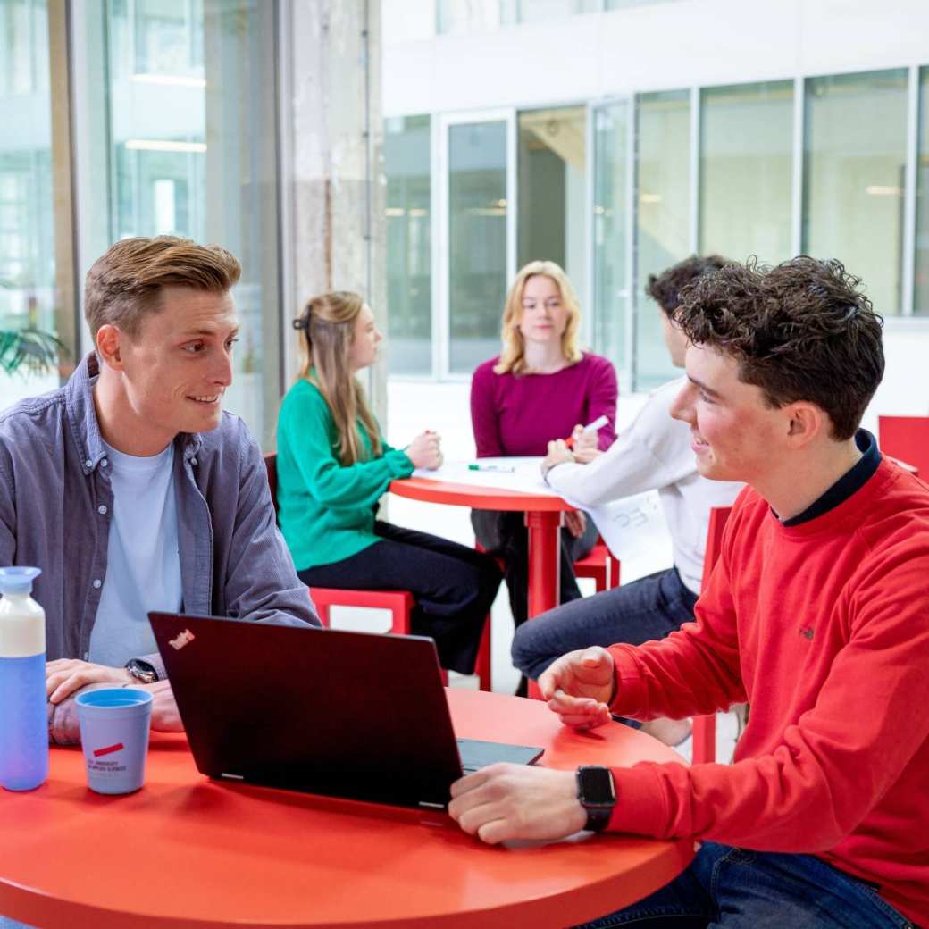 Studenten zittend aan tafel met flesje en laptop. Master Circulaire Economie 2024.