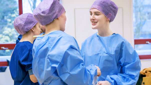 Studenten van de opleidingen tot  Operatieassistent en Anesthesiemedewerker staan in een groepje en lachen met elkaar.