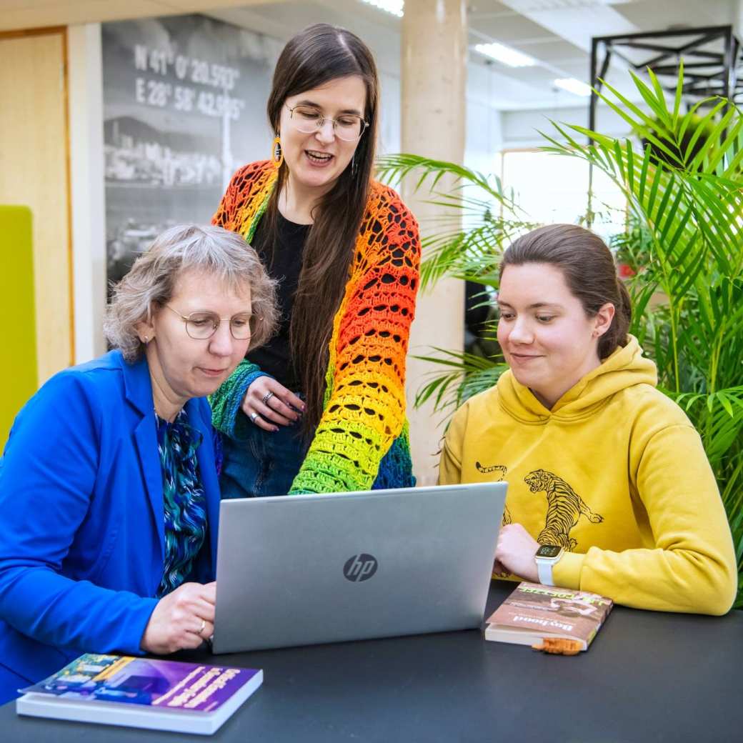 3 masterstudenten kijken samen op een laptop