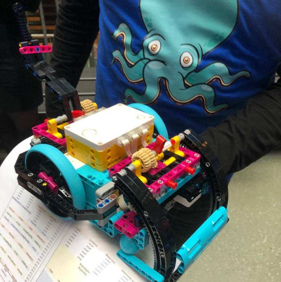 Een jongen met een octopus op zijn trui houdt een lego auto vast tijdens de region finale van de Lego League 2023