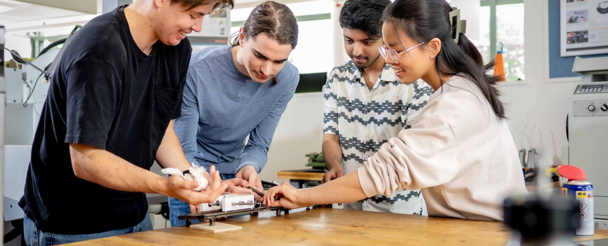 Studenten werktuigbouwkunde moeten samenwerken bij het op spanning brengen van een veer.