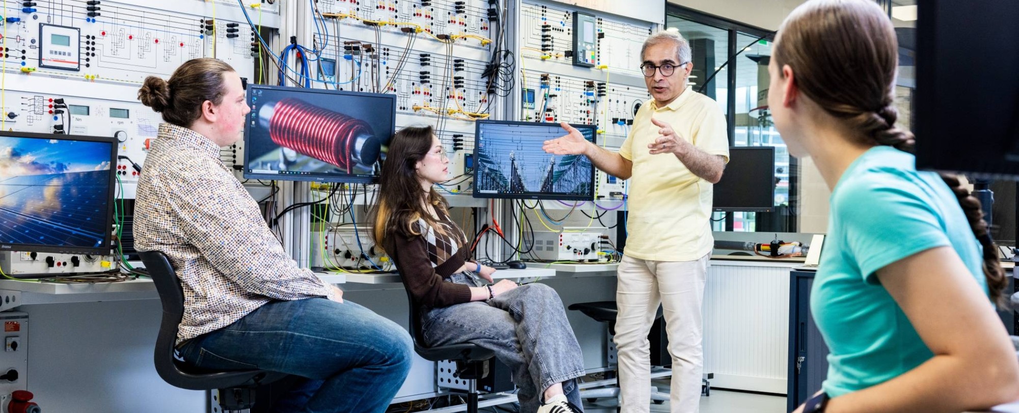 Studenten en docent elektrotechniek tijdens een les in het hoogspanningslab.