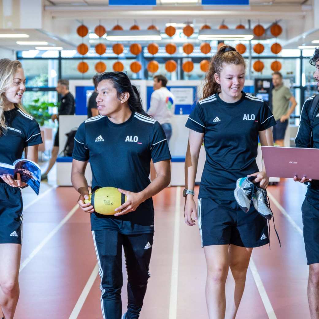 sportkunde en alo samen liggende foto studenten lopen over atletiekbaan binnen bij gymnasion selena esteban carlijn randy 2022