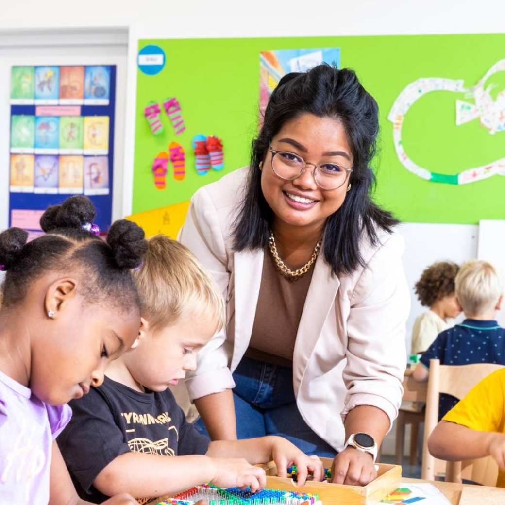 De lerares van de opleiding leraar basisonderwijs helpt de leerlingen bij het leggen van een puzzel