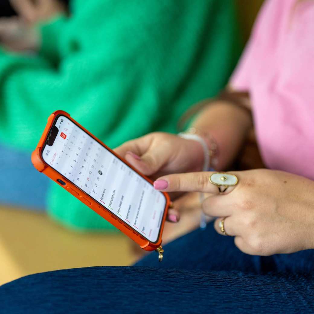Student houdt haar telefoon vast en wijst er met haar vinger iets op aan.