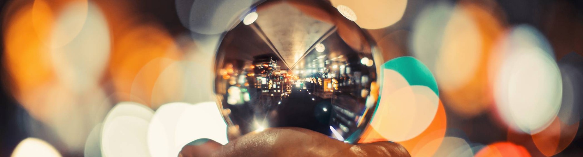 Een glazen bol met een stad op een hand met kleurige achtergrond lichtjes