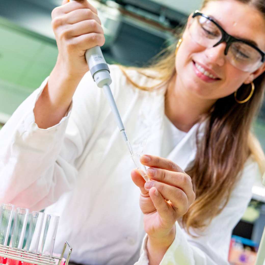 Student in het lab met reageerbuisjes en een pipet