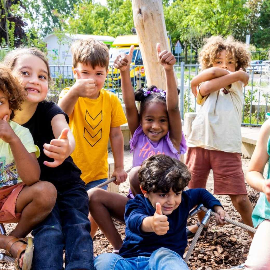 Zeven kinderen poseren buiten op het klimnet