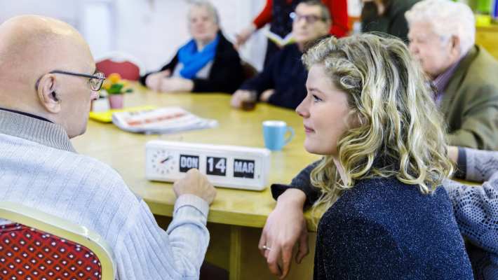 wijkatelier lindenholt- aan tafel studente hurkt en geeft uitleg kalenderklok