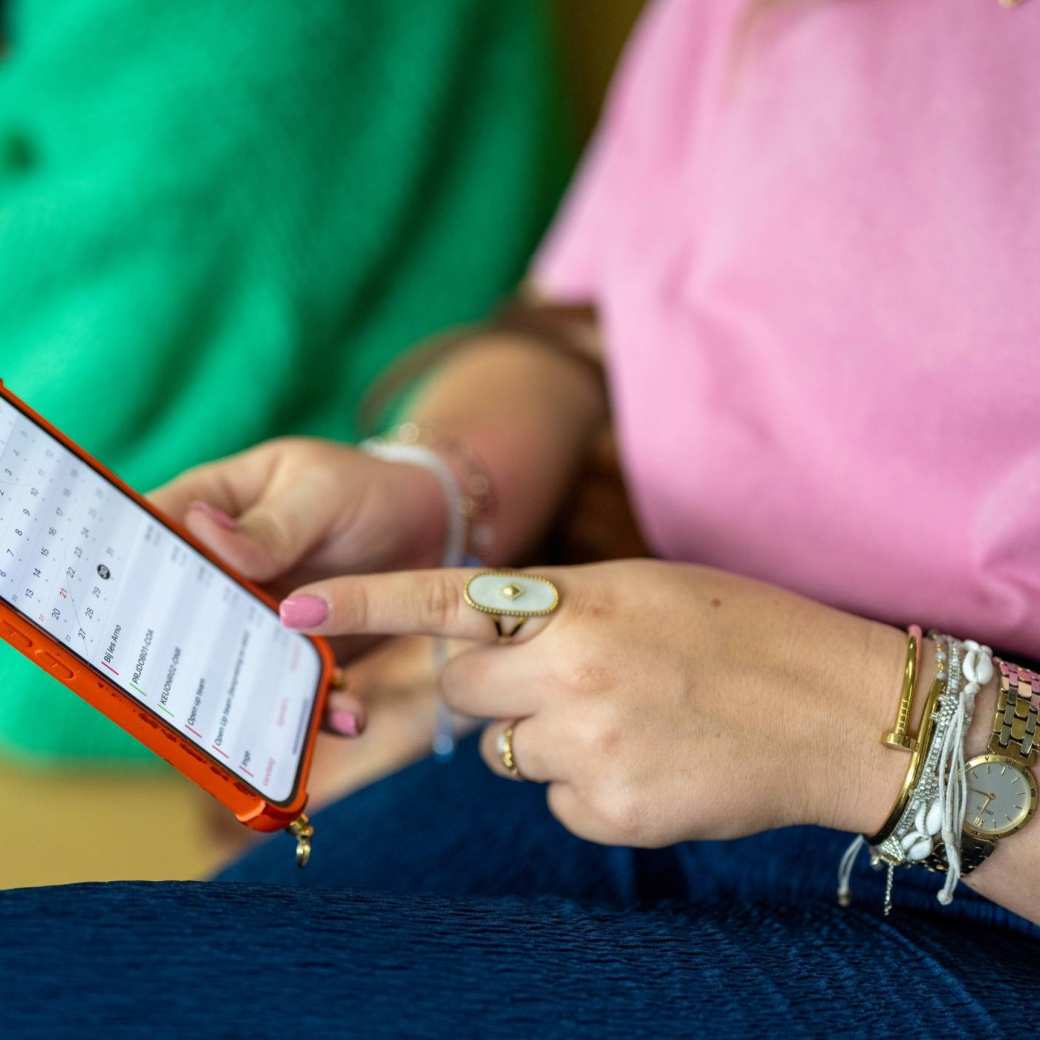 Student houdt haar telefoon vast en wijst er met haar vinger iets op aan. 