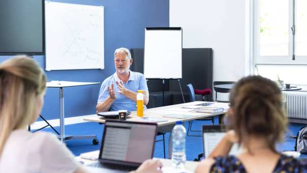 Docent geeft met handgebaren uitleg aan studenten