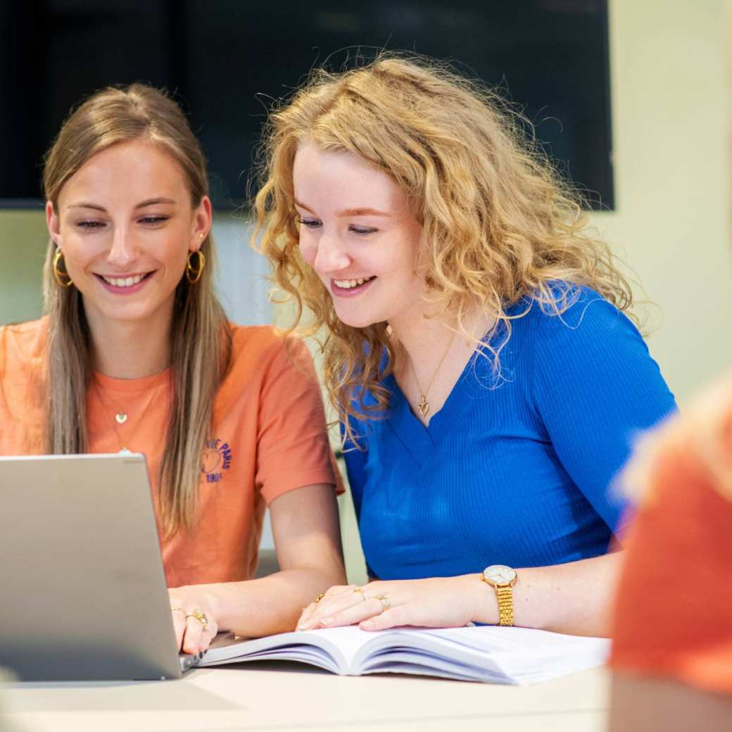 Verpleegkunde studenten kijken samen naar de laptop tijdens de les