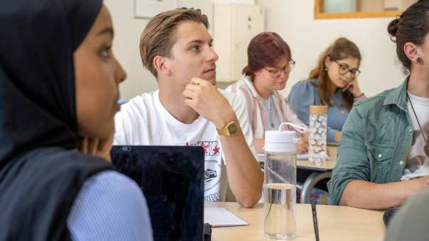 Studenten in klas, ingezoomd, luisteren naar de docent. 