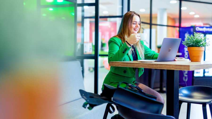 Vrouw drinkt koffie en kijkt naar een laptop op de HAN.