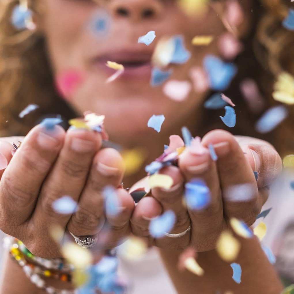 vrouw met confetti in handen en blaast