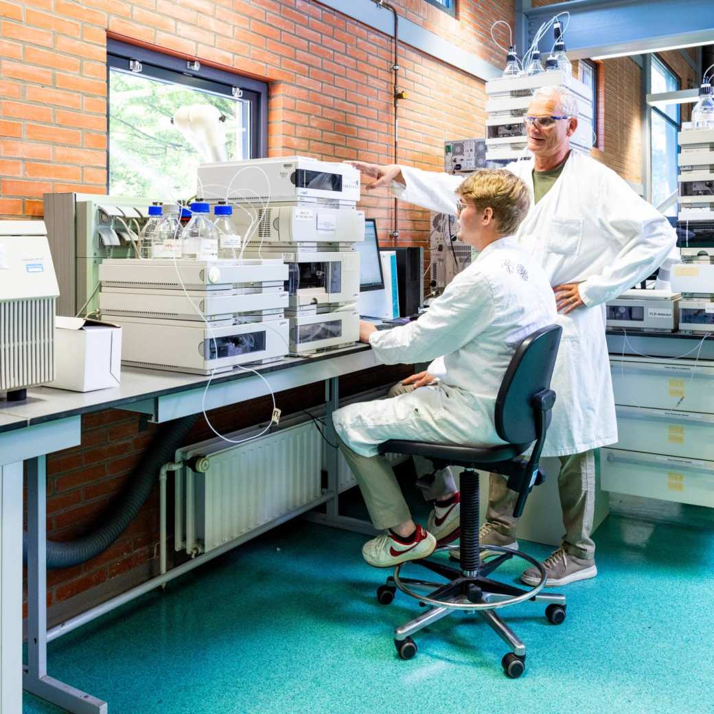 docent geeft uitleg aan student in chemie lab