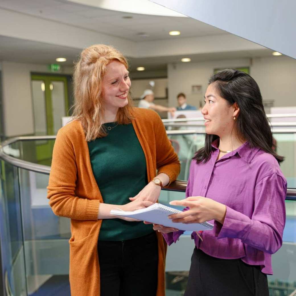 een student en een docent van de opleiding toegepaste psychologie aan het overleggen in de gang