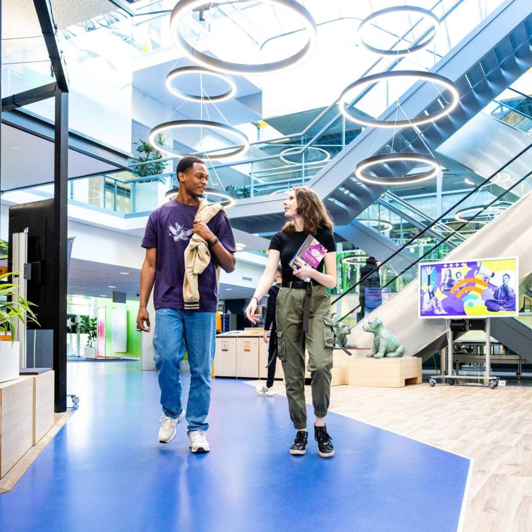 Studenten Learning and Development in Organisations (Opleidingskunde) lopen in de gang door het gebouw in Nijmegen