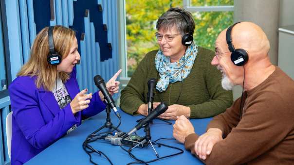 3 masterstudenten zitten in een podcaststudio met koptelefoons op