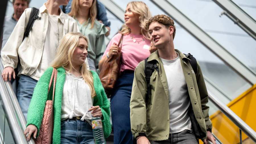Groepje studenten lopen samen door het gebouw LvS10, gaan de trap af.
