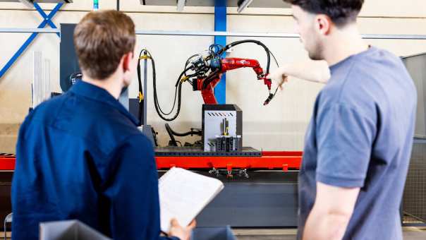 Technische Bedrijfskunde studenten Jort en Derk samen bij robot arm.