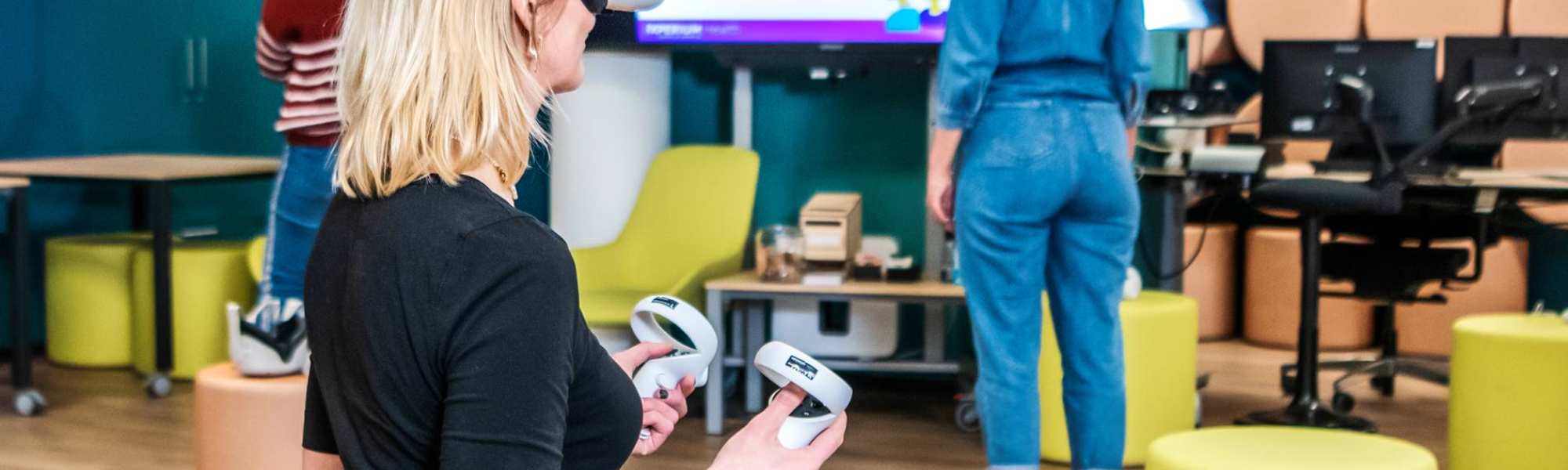 Foto van iXperium Health, waar 2 studenten en een docent een VR-bril op hebben.