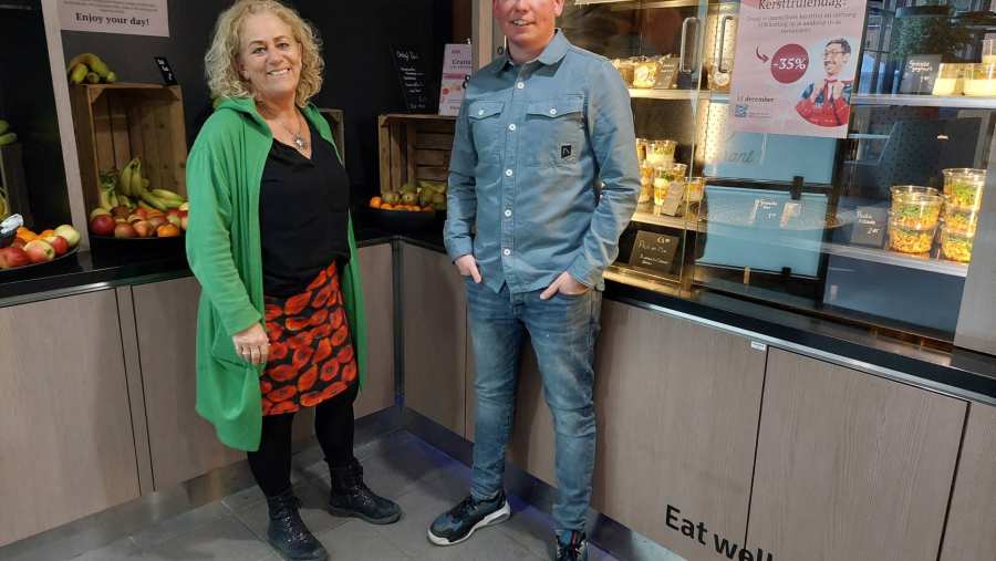 Hoofd facilitaire zaken en contracteigenaar, Karin Sanders-van Heijst, vestigingsmanager van Eurest, Erik van Bemmel bij de ingang van het restaurant van de HAN aan de Kapittelweg 33 in Nijmegen. Poster foute kersttruiendag op de achtergrond.