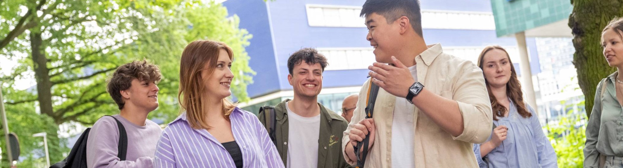 Groepje studenten staan buiten, met elkaar aan het kletsen, op de campus.