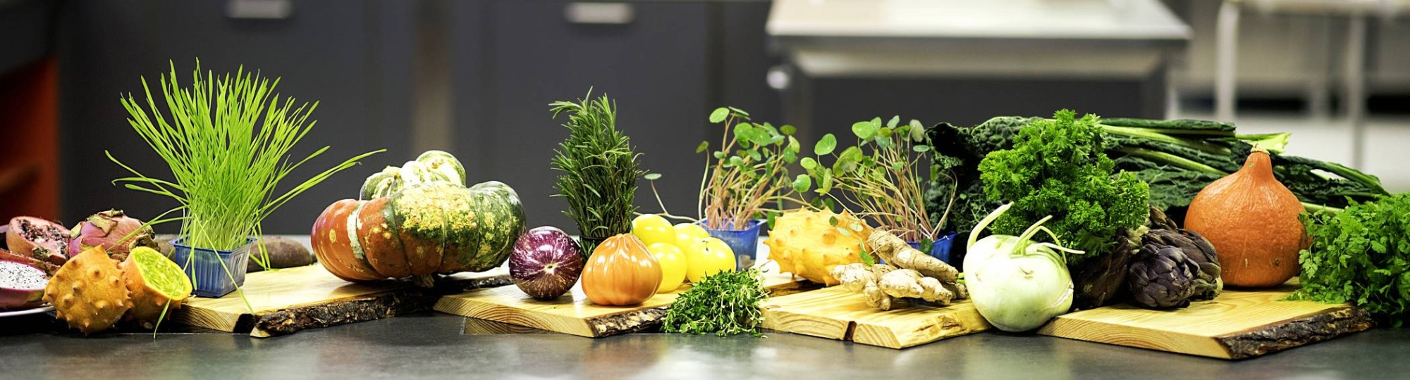 Een donkere tafel met daarop verschillende schalen met groenten en fruit zoals ui en gember