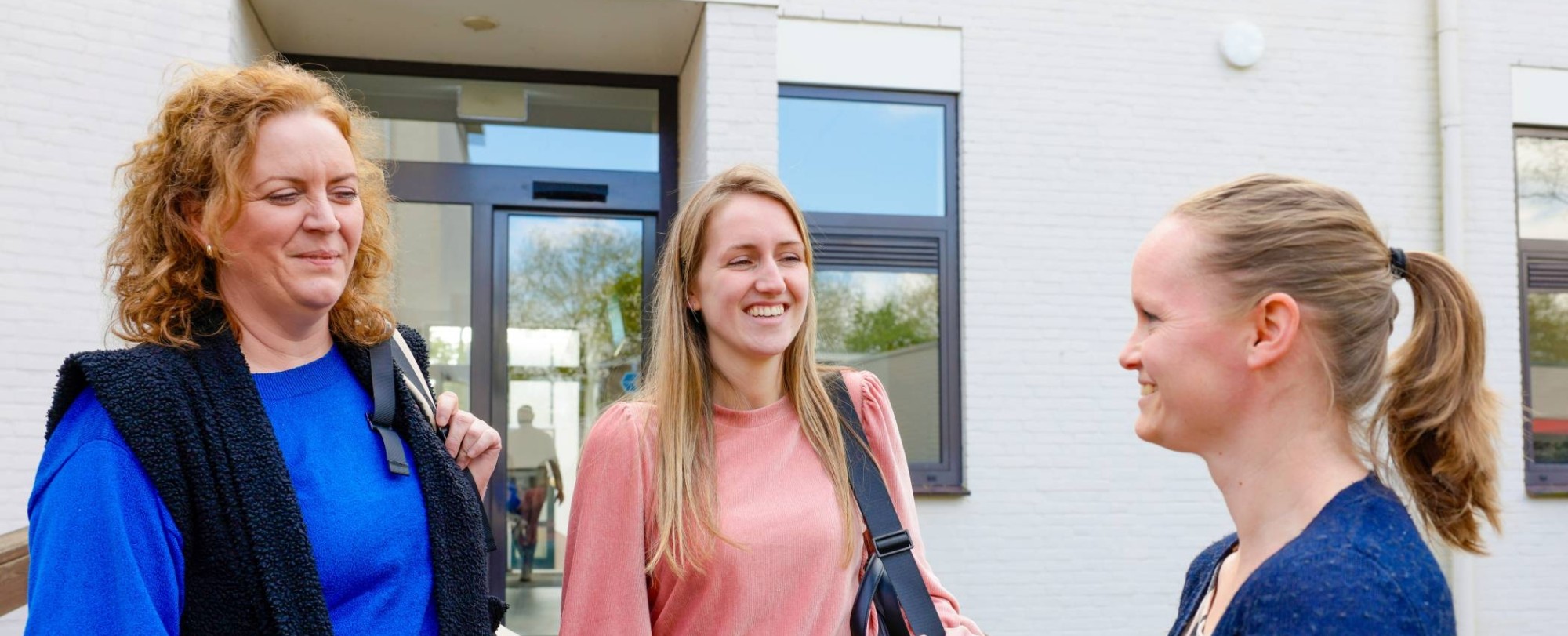 Twee mannen en twee vrouwen staan pratend op de gang