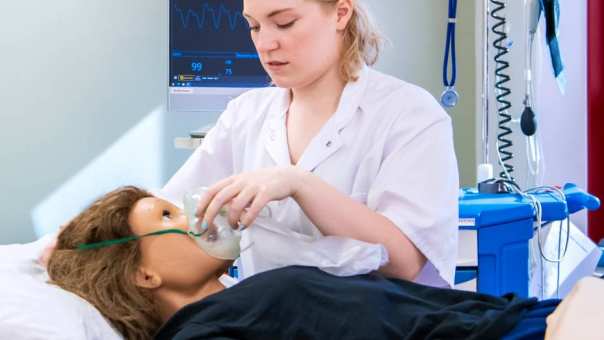 Student onderzoekt pop tijdens les Verpleegkunde voltijd
