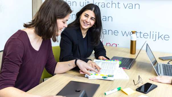 Studenten HBO-Rechten kijken in een wettenbundel