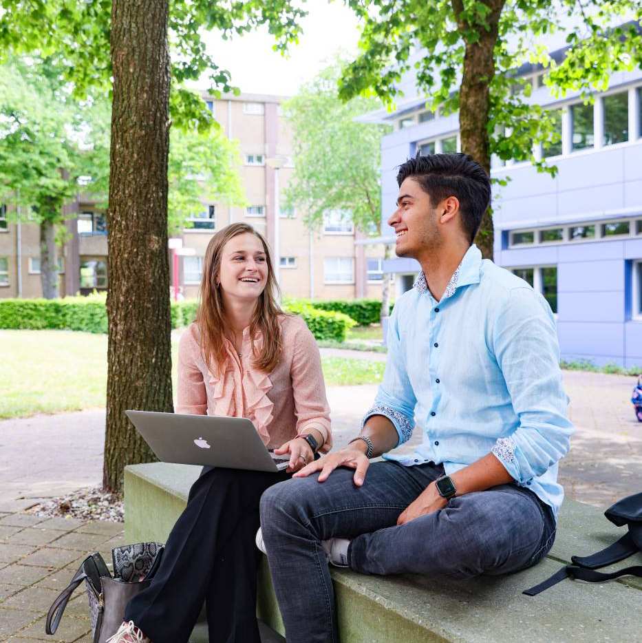 twee studenten van bedrijfskunde lachend buiten bij de HAN campus